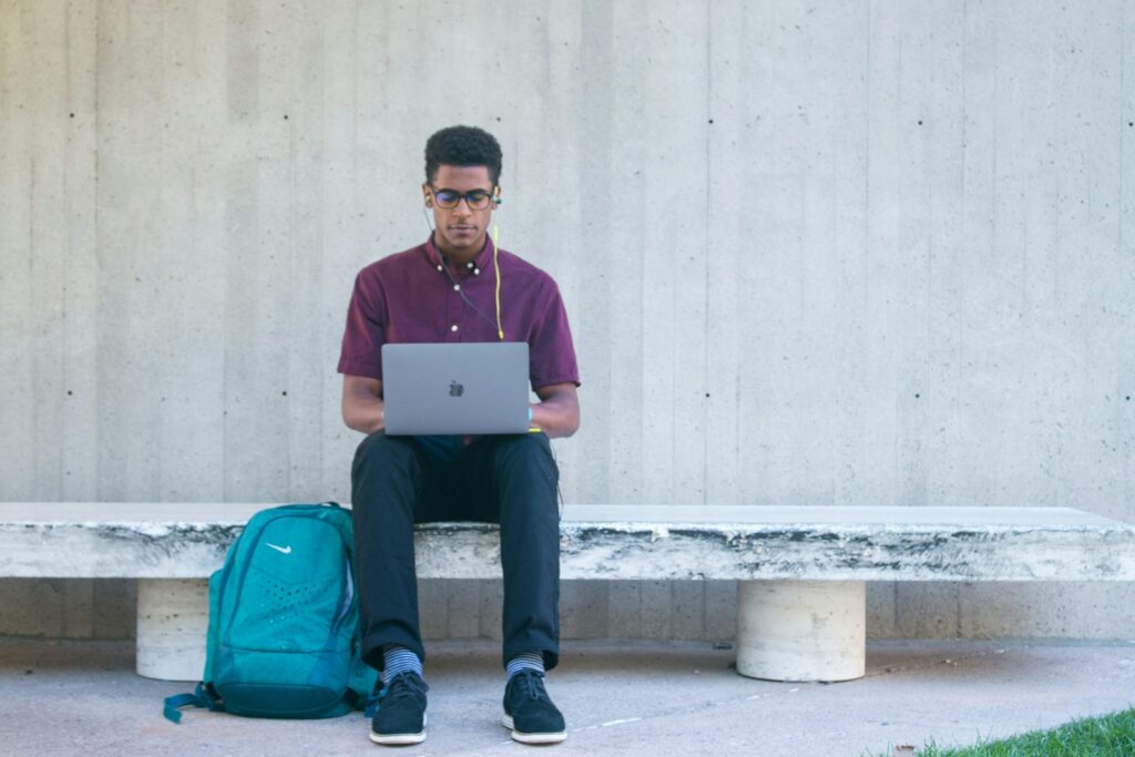 a man sitting on a bench with a laptop