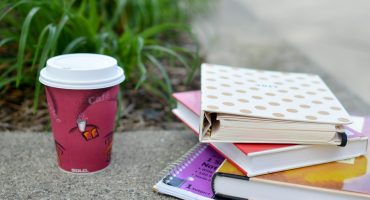 red and white cup beside book