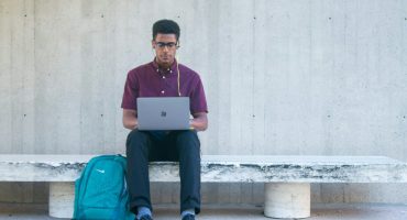 a man sitting on a bench with a laptop