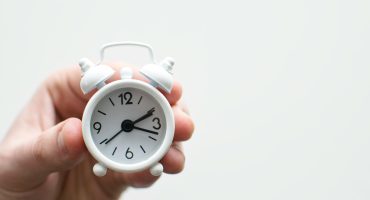 person holding white mini bell alarmclock