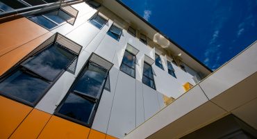 a tall building with lots of windows next to a blue sky